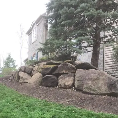 Natural stone retaining wall and landscape bed
