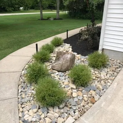 River rock bed with ornamental grasses and boulder accent
